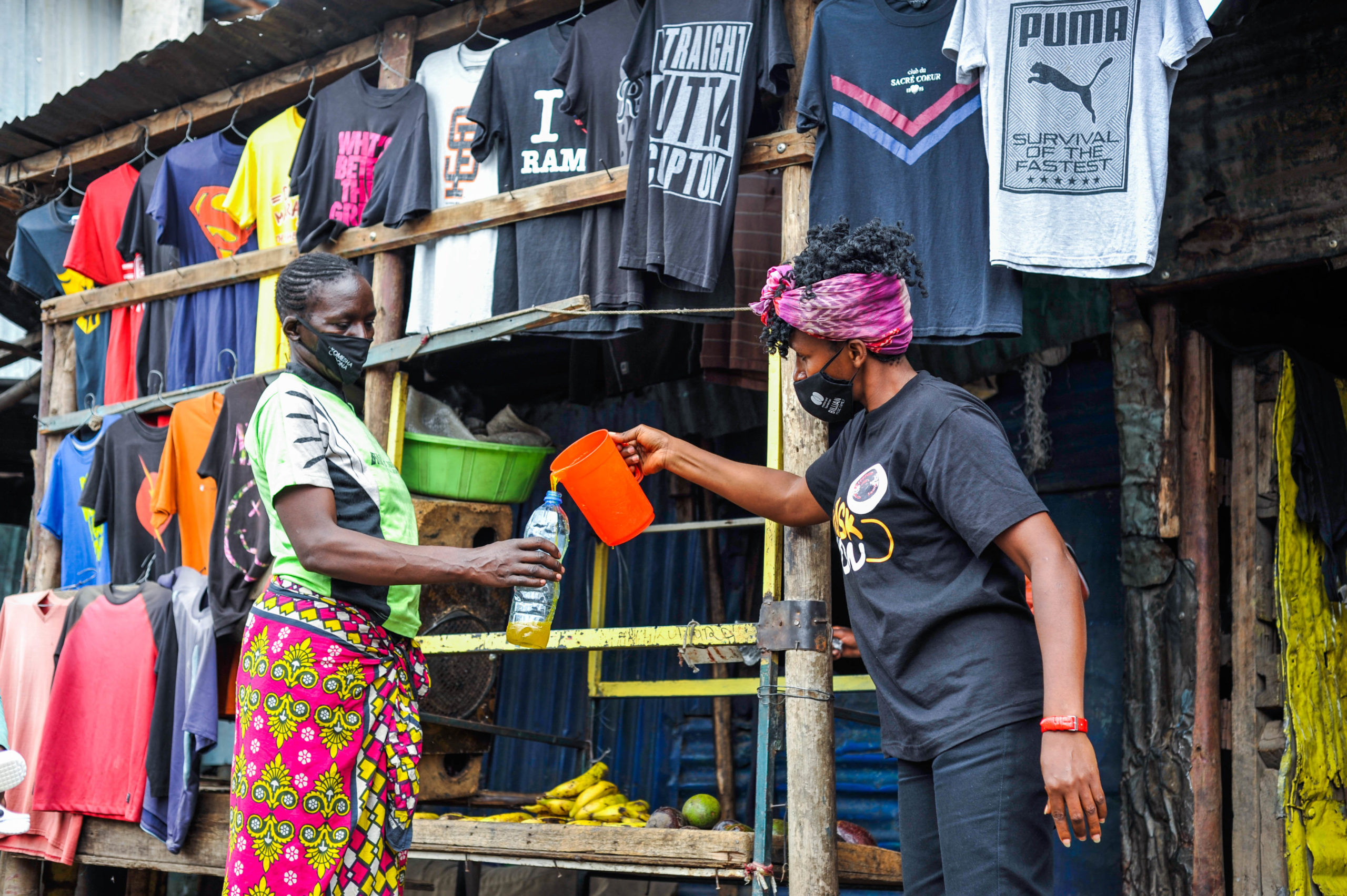 A volunteer from the Billian Music Family shares liquid soap with a lady resident in Mathare Slums, Nairobi, Kenya, during the second phase of the Public Awareness Campaign in 2021. Photo by Gerald Anderson